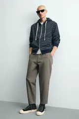 Pantalón de corte carrot fit confeccionado en tejido de algodón con estructura diagonal y efecto lavado. Presenta bolsillos frontales con bolsillo cerillero, bolsillos traseros de plastrón y cierre frontal con cremallera y botón.