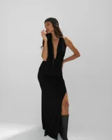 Vestido largo negro de corte ajustado, con escote profundo en V y espalda descubierta. Presenta un tajo lateral en la falda y un detalle de textura brillante en el borde del escote.