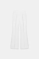 Pantalón de tiro alto en color negro, con diseño de corte recto y ligeramente acampanado. Presenta costuras verticales marcadas en el frente y bolsillos laterales de vivo.