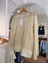 Sweater de punto calado color rosado, con diseño holgado, cuello redondo y mangas largas, que incluye una musculosa interior con terminación bordada en el bajo.