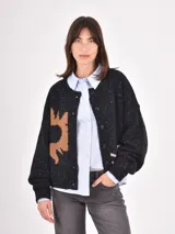 Cardigan de punto negro con diseño de sol en color tostado, cuello redondo y cierre frontal con botones. Presenta un tejido con motas de colores y corte holgado.