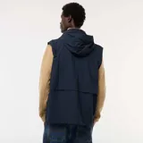 Chaqueta cortavientos azul marino con capucha, cierre frontal y bolsillos con solapa a la altura de la cintura. Presenta un diseño técnico y holgado.