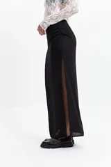 Falda larga negra de calce recto con tajo lateral alto y detalle fruncido en un lateral de la cintura.