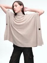 Poncho amplio de tejido de punto con cuello alto, diseño holgado y botones laterales decorativos.