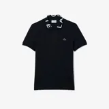 Chomba Lacoste de corte slim fit, color negro, con cuello tipo polo que presenta el nombre de la marca estampado en letras blancas. Incluye el logo del cocodrilo bordado en el pecho y cierre frontal con botones.