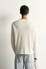 Remera polo de manga larga y calce regular fit en color blanco off-white, confeccionada en mezcla de algodón y lino, con cuello redondo y cartera con botonadura frontal.