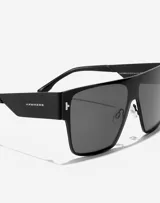 Lentes de sol Hawkers modelo Long Island, unisex, con montura cuadrada negra y lentes grises.