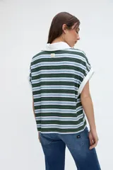 Musculosa tipo polo a rayas horizontales en tonos verdes, azules y blancos, con cuello y ribetes en contraste. Presenta media cartera de botones y tajos laterales en el dobladillo.