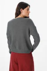 Sweater de punto negro con diseño de trenzas verticales en el frente y cuello redondo. Presenta un corte holgado con puños y ruedo acanalados.