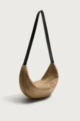 Bolso de hombro de gamuza marrón con diseño curvado, compartimento principal con cierre de cremallera y asa larga de cuero negro.