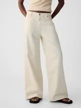 Jean de corte baggy y tiro medio, color crudo, con diseño de cinco bolsillos y cierre frontal con botón y cremallera.