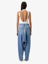Jean sarouel de denim azul con corte holgado y aberturas verticales delanteras con cremallera.