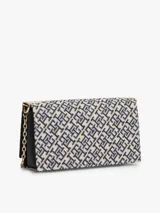 Cartera cruzada Tommy Hilfiger con diseño jacquard en tonos azul y beige, solapa con detalle de cuero sintético negro en la base y cierre con broche metálico dorado con monograma de la marca. Incluye correa de cadena dorada.