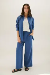 Pantalón de lino azul de corte recto y amplio, con cintura elastizada, cierre de cremallera y botón. Presenta detalles de pespunte blanco en los bordes de los bolsillos.