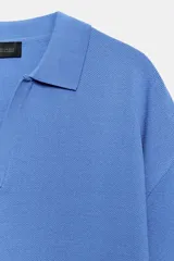 Polo amplio de punto color celeste, con cuello y escote en V, de manga corta.