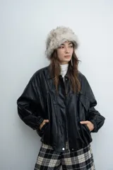 Chaqueta de cuero sintético color marrón con capucha y solapas amplias en tela escocesa a cuadros. Posee cierre frontal, puños elásticos y diseño de corte holgado.