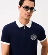 Remera polo Marfinno de manga corta, color bordó con cuello y puños en contraste de color blanco. Presenta cierre frontal corto y un escudo bordado en el pecho.