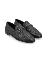 Mocasines negros de cuero con diseño entrelazado, detalle de estribo metálico en el empeine y suela plana.