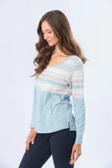 Remera de algodón con poliéster, de manga larga, con estampado de rayas horizontales en tonos beige, azul claro, azul grisáceo y blanco. Tiene un corte clásico y escote redondo.