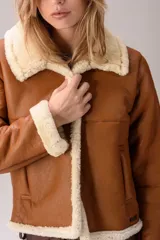 Gamulán marrón de cuero con interior y detalles de corderito sintético en cuello, solapas, puños y ruedo. Cuenta con bolsillos laterales y diseño abrigado.