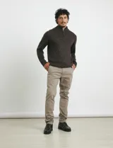 Pantalón de vestir verde oliva, de corte slim fit, sin pinzas, con bolsillos laterales y traseros. Se ajusta a la cintura con cinturón de cuero marrón.