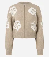 Cardigan cropped color beige con estampado de flores blancas, cuello redondo, cierre frontal con cremallera y mangas largas.