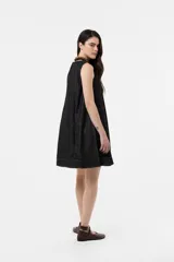 Vestido corto sin mangas de denim negro, con silueta evasé, calce suelto y costuras pespunteadas a contratono.
