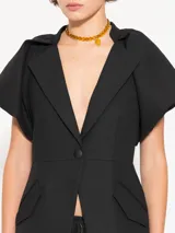 Blazer negro de lanita viscosa con cuello mao y mangas ranglan abullonadas tipo balloon con frunces en la unión con el cuello. Incluye pinza lateral que mejora el calce en la sisa, bolsillos ojal con tapa y cierre con broche bombé super black.