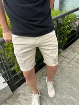 Bermuda de jean color beige, con roturas y dobladillo en las piernas.