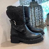 Bota de cuero negro con caña media, hebilla lateral y suela track.