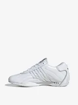 Zapatillas Adidas Adiracer Lo color blanco, inspiradas en los coches de carreras. Confeccionadas en cuero y material sintético, con las tres tiras características de la marca en los laterales.