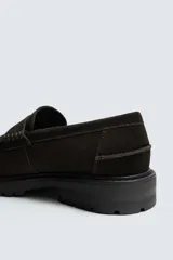 Mocasín de vestir para hombre, confeccionado en piel con acabado de serraje en color marrón oscuro. Presenta un diseño clásico con detalle de antifaz en el empeine, horma redonda y una suela track robusta de goma.