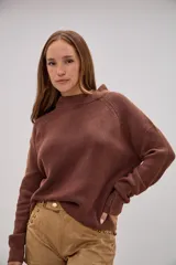 Sweater de tejido de punto color marrón chocolate, con cuello redondo y mangas largas con puños ajustados. Presenta un corte recto y holgado con el ruedo ligeramente asimétrico.