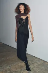 Top lencero negro de escote pico y tirantes finos. Presenta aplicación de encaje a tono en el escote y el bajo asimétrico.