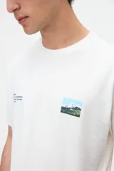 Remera de manga corta color blanco con diseño gráfico fotográfico y texto en el frente.