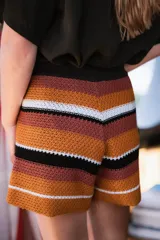 Short tejido a crochet a rayas horizontales en tonos marrón, celeste y blanco. Tiene cintura elastizada y tiro alto.
