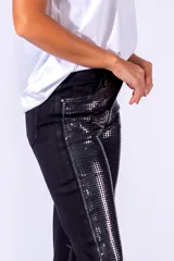 Pantalón de jean gris con apliques de lentejuelas plateadas en forma de cuadrícula.