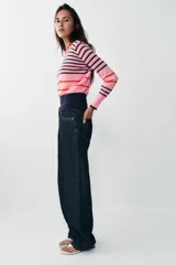 Jersey de punto de cuello redondo y manga larga con puños ajustados. Presenta un diseño de rayas horizontales en tonos rosa, azul marino y detalles en rojo.