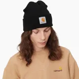 Gorro de lana tejido en punto acanalado, color negro, con borde doblado y parche cuadrado con el logo de Carhartt bordado en el frente.