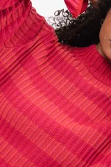 Buzo de tejido de punto con cuello alto, manga larga y diseño a rayas horizontales en tonos fucsia y naranja.