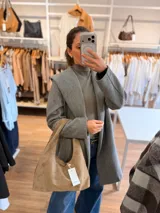 Cartera tipo hobo de diseño flexible y caída natural, confeccionada en material con textura simil gamuza. Cuenta con asa corta integrada para llevar al hombro, cierre superior y bolsillo interior con cierre.