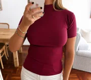 Polera de manga corta color bordó, con cuello alto y ajuste al cuerpo, confeccionada en tejido de microfibra con textura acanalada.