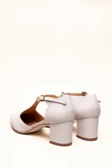 Sandalia de cuero color bordó, con acabado charolado, punta fina y tacón cuadrado de 5 cm. Presenta una tira en forma de T sobre el empeine y una correa con hebilla alrededor del tobillo.