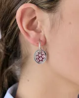 Aros tipo argolla de plata con dije circular de resina con diseño estampado de flores pequeñas en color bordó sobre fondo blanco.