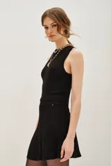 Top sin mangas con cuello halter, confeccionado en tejido de punto con acabado metalizado. Presenta un ajuste al cuerpo y diseño minimalista.