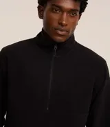 Saco de polar negro con cuello alto y cierre frontal parcial, de manga larga y diseño de corte recto.