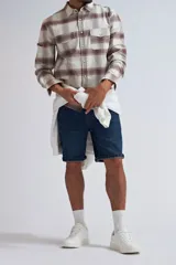 Camisa de manga larga con estampado de cuadros en tonos beige y marrón, confeccionada con cierre frontal de botones y bolsillos en el pecho.