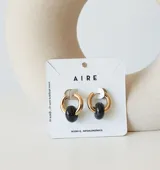 Aros de acero quirúrgico dorado con dije colgante en forma de argolla de piedra natural negra con destellos.