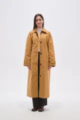 Trinchera larga de corte holgado, con cuello solapa, cierre frontal con botones y cinturón ajustable a la cintura. Cuenta con mangas largas y bolsillos laterales.