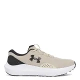 Championes de running Under Armour modelo Charged Surge 4, color beige con detalles en negro y suela blanca. Confeccionados en malla transpirable con refuerzos sintéticos laterales para mayor soporte y entresuela con tecnología Charged Cushioning para una amortiguación reactiva.